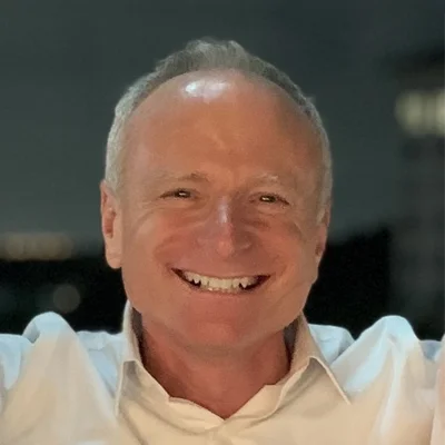 A headshot photo of Dr. Mitch Siegal wearing a white collared shirt and smiling at the camera